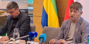 Od lewej: zastępca wójta gminy Chojnice Janusz Szczepański i wójt Zbigniew Szczepański. Mężczyźni siedzą przy stole konferencyjnym z mikrofonami. Wójt przemawia. W tle widoczne są flagi oraz grafika przedstawiająca jezioro. Zdjęcie ilustruje news o tym, że gmina Chojnice zorganizuje szkolenie dla wszystkich sołtysów