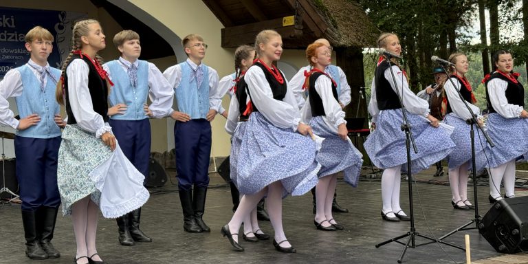 Grupa dzieci w strojach ludowych tańczy na scenie podczas 49. Wielewskiego Turnieju Gawędziarzy