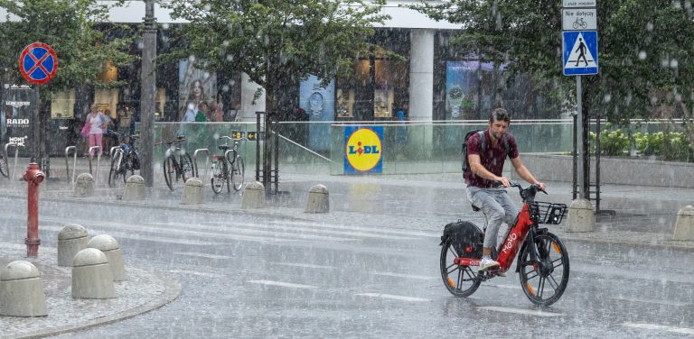 Rowerzystka jedzie ulicą w trakcie ulewnego deszczu