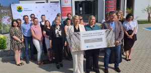 Grupa osób stoi przed Urzędem Gminy Parchowo. Trzymają wspólnie czek z napisem "USUWANIE WYROBÓW ZAWIERAJĄCYCH AZBEST. 1 593 572 ZŁ DLA WOJEWÓDZTWA POMORSKIEGO"