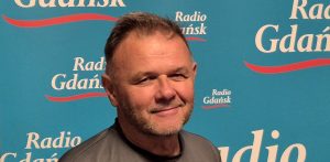 Na zdjęciu znajduje się Adam Hlebowicz, historyk. Stoi na tle ścianki z napisami "Radio Gdańsk".