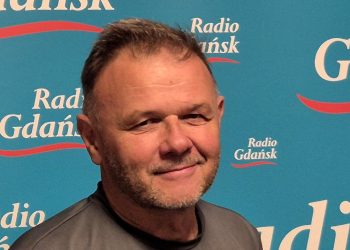Na zdjęciu znajduje się Adam Hlebowicz, historyk. Stoi na tle ścianki z napisami "Radio Gdańsk".