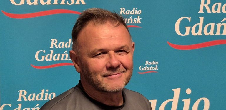 Na zdjęciu znajduje się Adam Hlebowicz, historyk. Stoi na tle ścianki z napisami "Radio Gdańsk".