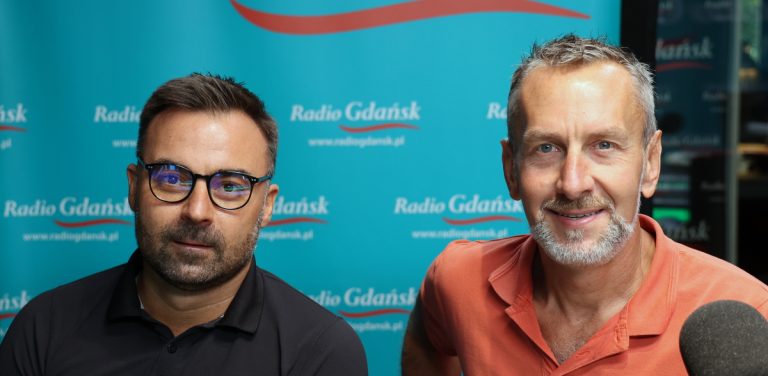 Mikołaj Lipiński w okularach i czarnej koszulce polo oraz Rafał Dadej w pomarańczowej koszulce polo w studiu Radia Gdańsk, na tle niebieskiej ścianki z logo stacji. W audycji "Ludzie i Pieniądze" rozmawiali z Iwoną Wysocką o o wdrożeniu dyrektywy NIS 2, ustawie o Krajowym Systemie Cyberbezpieczeństwa oraz odpowiedzialności i wysokich karach grożących zarządom firm za brak odpowiednich zabezpieczeń cyfrowych