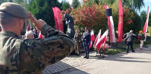 Światowy Dzień Sybiraka w Gdańsku. Żołnierz salutujący przed Pomnikiem Golgoty Wschodu na Cmentarzu Łostowickim w Gdańsku. Przy pomniku stoi warta honorowa w otoczeniu biało-czerwonych flag i flag Gdańska.