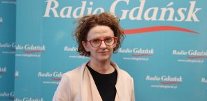 Kobieta w okularach w czerwonych oprawkach i jasnej narzutce na tle niebieskiej ścianki z logo Radia Gdańsk - pełnomocniczka prezydenta Sopotu ds. praw człowieka i koordynatorka Sopockiej Jesieni Zdrowia Psychicznego