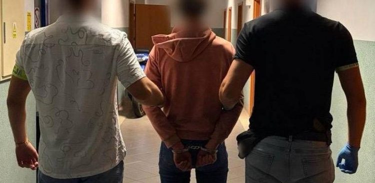 Dwaj nieumundurowani policjanci prowadzą korytarzem skutą kajdankami kobietę w różowej bluzie z kapturem, podejrzaną o podpalenie wiaty śmietnikowej oraz supermarketu na gdańskiej Oruni. Głowy osób na zdjęciu są zamazane