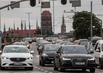 Na zdjęciu wiele samochodów na ulicy. W tle panorama Gdańska.