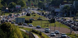 Widok z góry na wielopasmową arterię miejską w Gdańsku (ul. Słowackiego) w słoneczny dzień. Na jezdniach widać duże natężenie ruchu i długie sznury samochodów stojących w korku
