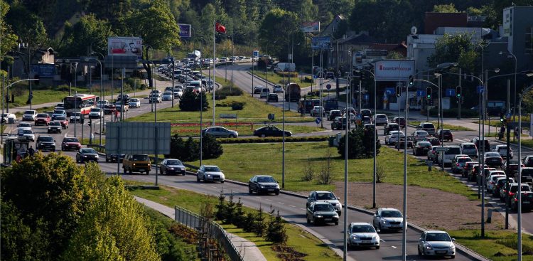 Widok z góry na wielopasmową arterię miejską w Gdańsku (ul. Słowackiego) w słoneczny dzień. Na jezdniach widać duże natężenie ruchu i długie sznury samochodów stojących w korku