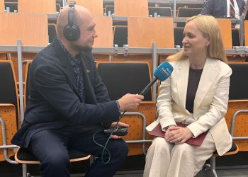 Na zdjęciu mężczyzna w słuchawkach trzyma mikrofon przy kobiecie, która się uśmiecha.