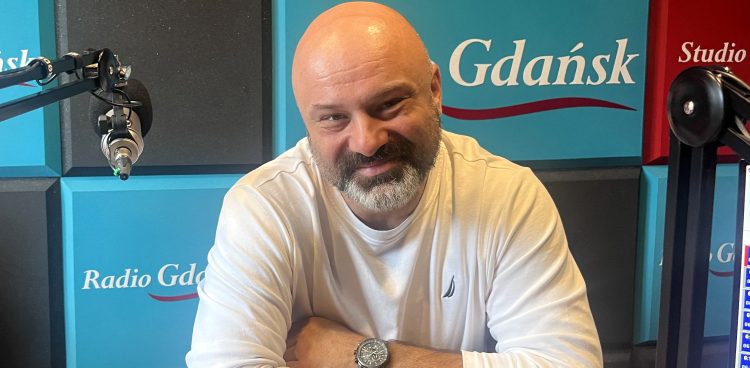 Uśmiechnięty, łysy mężczyzna z siwiejącą brodą w białej bluzce – ratownik Grzegorz Załupka – siedzi przy mikrofonie w studiu Radia Gdańsk. Specjalista mówił o bezpieczeństwa i i zasadach radzenia sobie przez pierwsze 72 godziny w sytuacjach kryzysowych, takich jak powódź czy ewakuacja