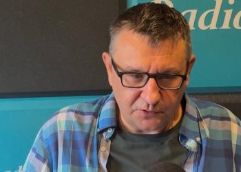 Mężczyzna w okularach w ciemnych oprawkach i niebiesko-turkusowej koszuli w kratę - Krzysztof Szablowski, trener koszykarzy Energa Czarnych Słupsk - przed mikrofonem w studiu Radia Gdańsk