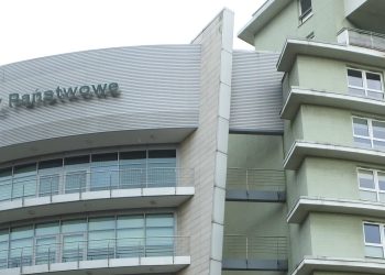 Fragment wielopiętrowego budynku biurowo-mieszkalnego z widocznym na zaokrąglonej elewacji logotypem oraz napisem "Lasy Państwowe". Do sądu wraca sprawa byłych przedstawicieli kierownictwa instytucji na Pomorzu, oskarżonych o przekroczenie uprawnień i próbę sprzedaży lokali mieszkalnych w Gdyni, co mogło narazić Lasy Państwowe na szkodę majątkową