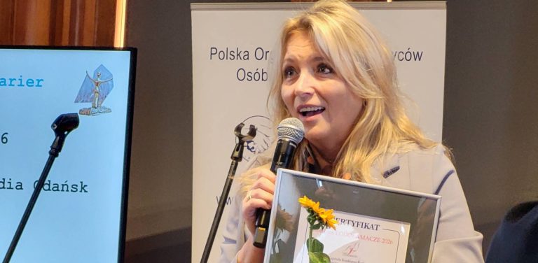Beata Gwoździewicz przemawia do mikrofonu, trzymając w rękach pamiątkowy certyfikat konkursu "Lodołamacze 2026". W tle widoczny ekran z prezentacją i logo POPON.