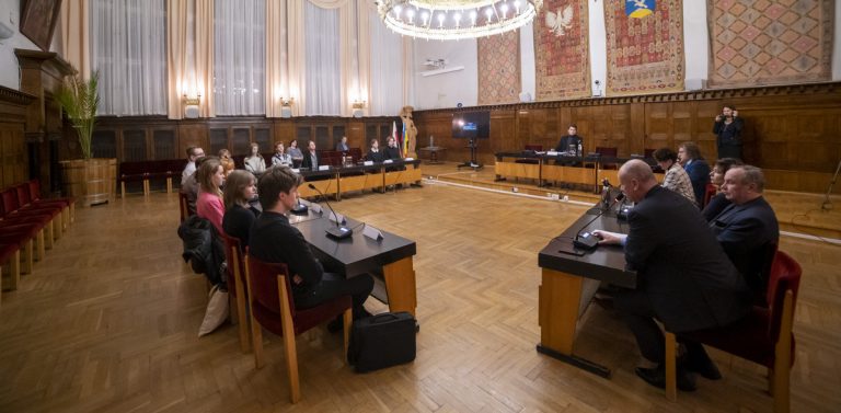 Na zdjęciu Pierwsza Sesja Młodzieżowej Rady Miasta Sopotu w 2022 roku. Młodzież i radni siedzą przy stołach w Urzędzie Miasta.