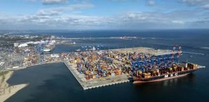 Widok z lotu ptaka na terminal kontenerowy w Porcie Gdańsk z dużym kontenerowcem MSC przy nabrzeżu, suwnicami oraz placem składowym wypełnionym kontenerami na tle Zatoki Gdańskiej. W pierwszych ośmiu miesiącach 2026 roku port obsłużył rekordowe 57,7 mln ton ładunków, a kluczowym motorem sierpniowego historycznego wyniku (ponad 8 mln ton) był dynamiczny, kilkunastoprocentowy wzrost przeładunków drobnicy i kontenerów