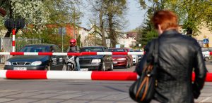 Zamknięte rogatki na przejeździe kolejowym w Gdańsku. Czekają samochody i motocyklista. Zdjęcie ilustruje temat modernizacji trasy z Lipusza do Bytowa. PKP PLK planuje tam montaż rogatek na połowie przejazdów. Mieszkańcy mają czas do końca września na składanie wniosków dotyczących dostępu do nich