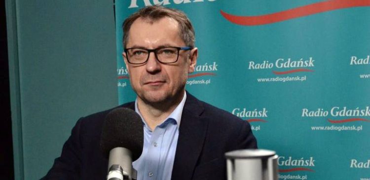 Sławomir Kiszkurno w okularach i ciemnej marynarce przed mikrofonem w studiu Radia Gdańsk. W audycji "Gość Radia Gdańsk" mówił o stratach finansowych i wyzwaniach dla gospodarki odpadami po wprowadzeniu systemu kaucyjnego