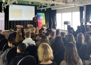 Forum Zdrowia Psychicznego w Centrum Kultury Mamuszki w Sopocie. Prelegentka stojąca na scenie z mikrofonem przemawia do sali pełnej młodzieży. W tle widoczny jest ekran z programem spotkania, banery z herbem Sopotu i logo Fundacji LPP oraz fotele przygotowane do dyskusji.