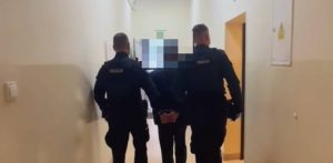 Dwaj umundurowani policjanci prowadzą korytarzem skutego kajdankami mężczyznę. To pijany maszynista, który przytrzasnął drzwiami kobietę z wózkiem na stacji kolejowej Racławki pod Chojnicami