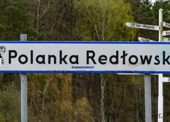 Na zdjęciu znajduje się napis Polanka Redłowska. Zdjęcie na tle lasu.