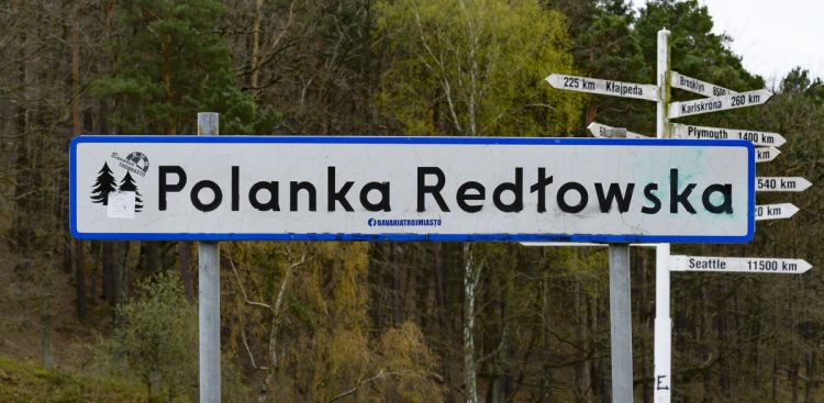 Na zdjęciu znajduje się napis Polanka Redłowska. Zdjęcie na tle lasu.