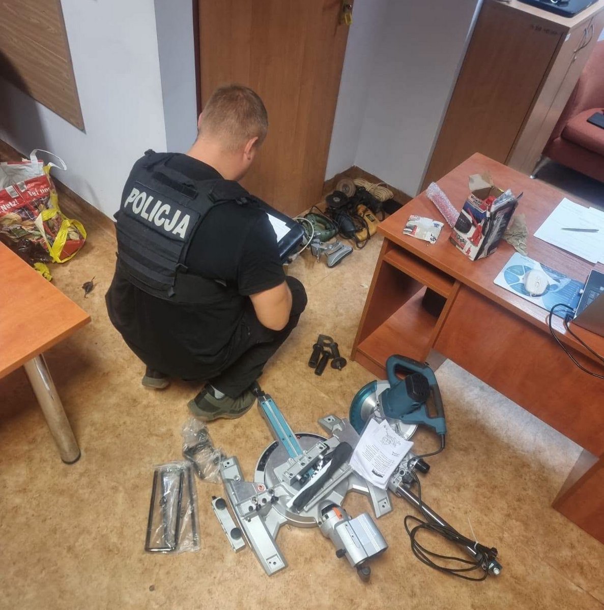 Policjant kuca przy skradzionych przedmiotach