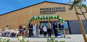 Na zdjęciu przedszkole samorządowe, przed którym stoją urzędnicy i dzieci. Uwieczniono moment przecięcia wstęgi