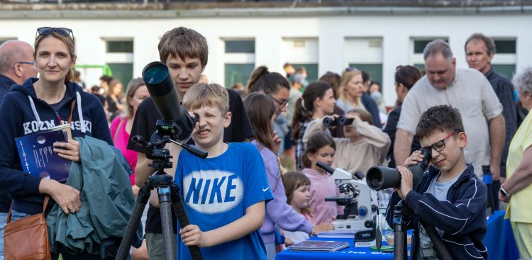 Na zdjęciu grupka dzieci która znajduje się pod Sopockim obserwatorium astronomicznym. Każdy z osobna ma swój teleskop i patrzą w niebo