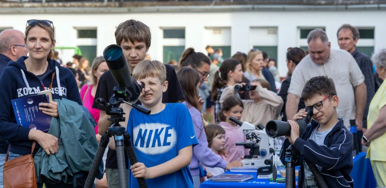 Na zdjęciu grupka dzieci która znajduje się pod Sopockim obserwatorium astronomicznym. Każdy z osobna ma swój teleskop i patrzą w niebo