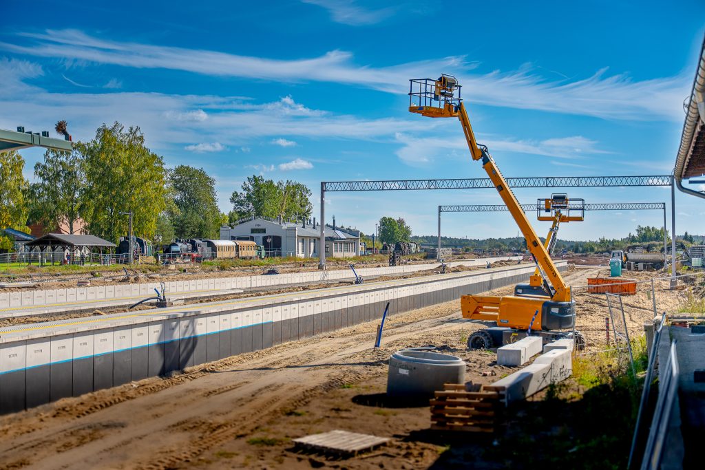 Plac budowy infrastruktury kolejowej i drogowej z widocznymi dźwigami i koparkami