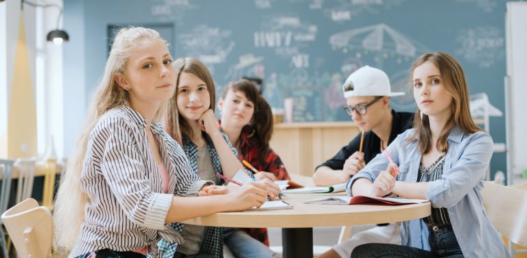Na zdjęciu uczniowie w sali lekcyjnej siedzą przy jednym stoliku