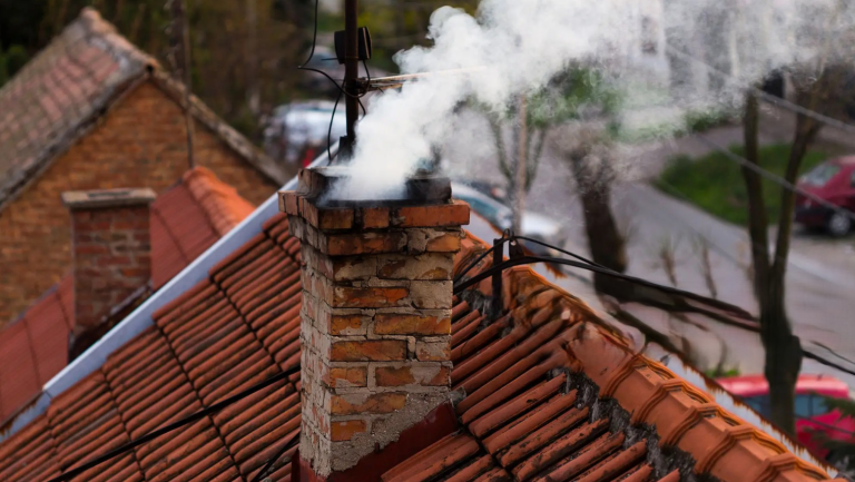 Na zdjęciu widać ceglany komin z wydobywającym się z niego białym dymem