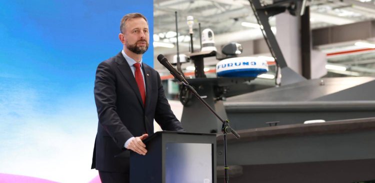 Władysław Kosiniak-Kamysz przemawia przy mównicy w hali fabrycznej na tle bezzałogowej jednostki morskiej z radarem Furuno